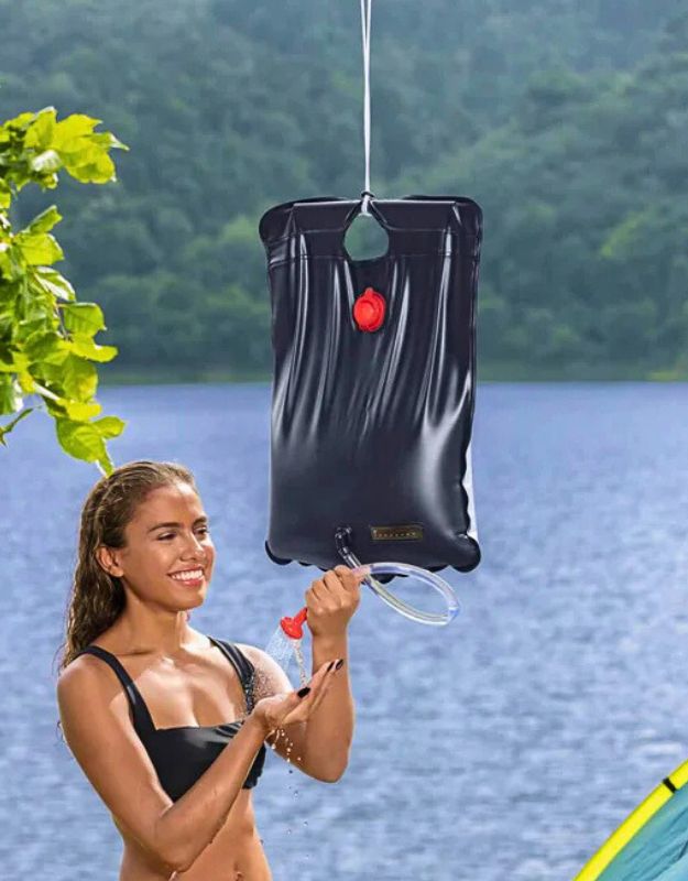 Woman enjoying a refreshing shower outdoors using the Bestway 58224 solar-heated camping shower bag.
